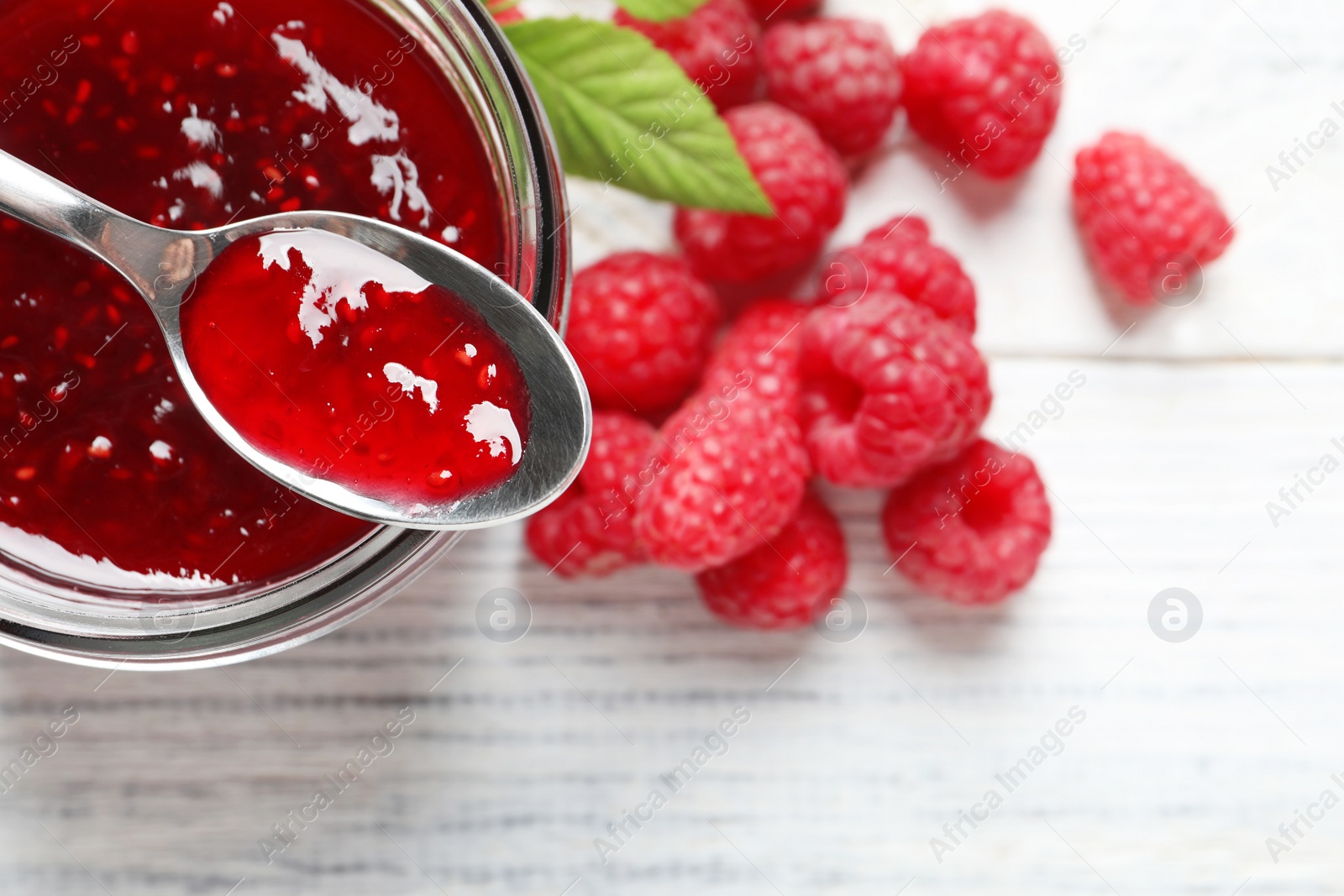 Image of Sweet raspberry jam and fresh berries on white wooden table, flat lay