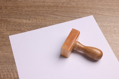 One stamp tool and sheet of paper on wooden table, closeup. Space for text