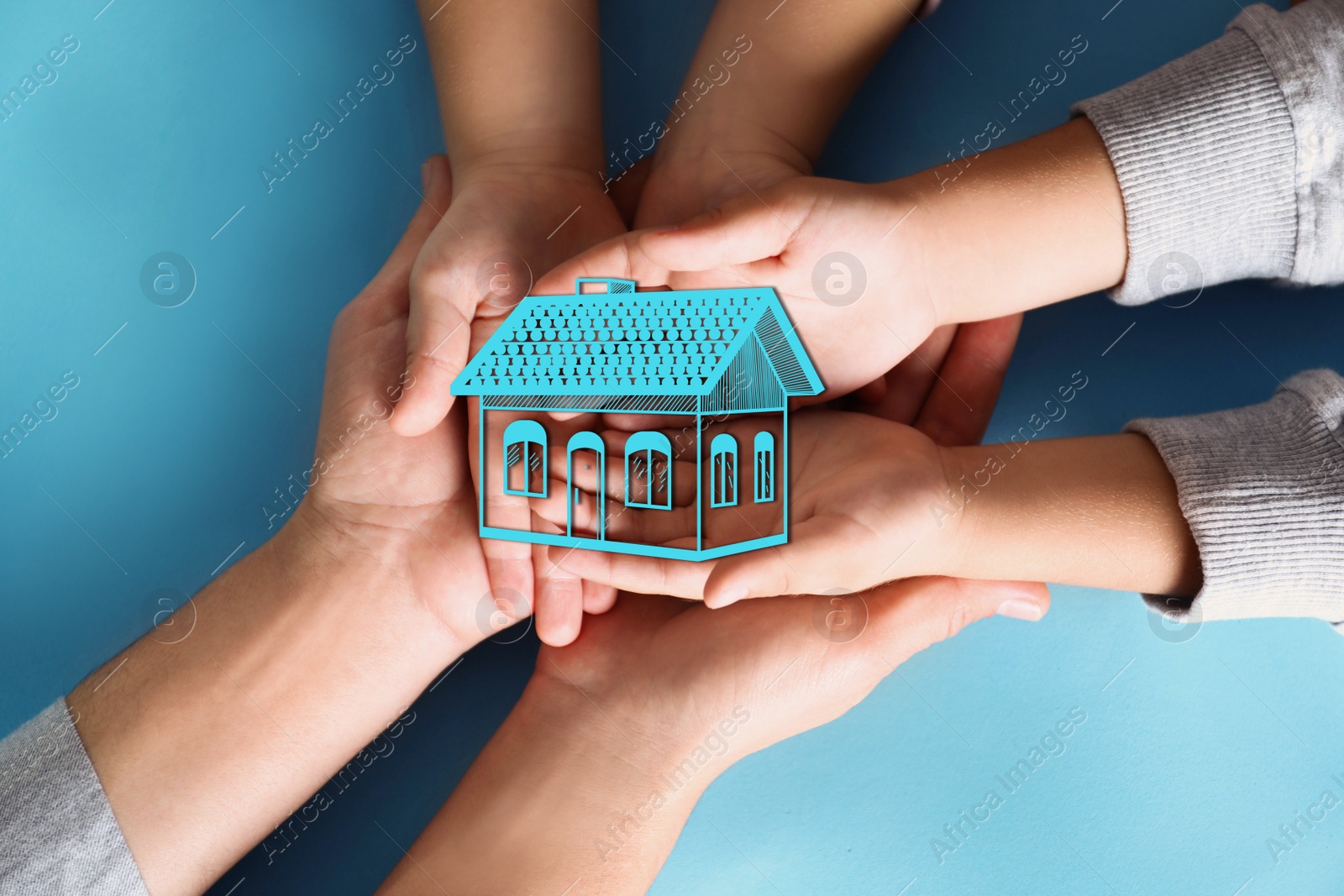 Image of Home security concept. Family holding house on light blue background, top view