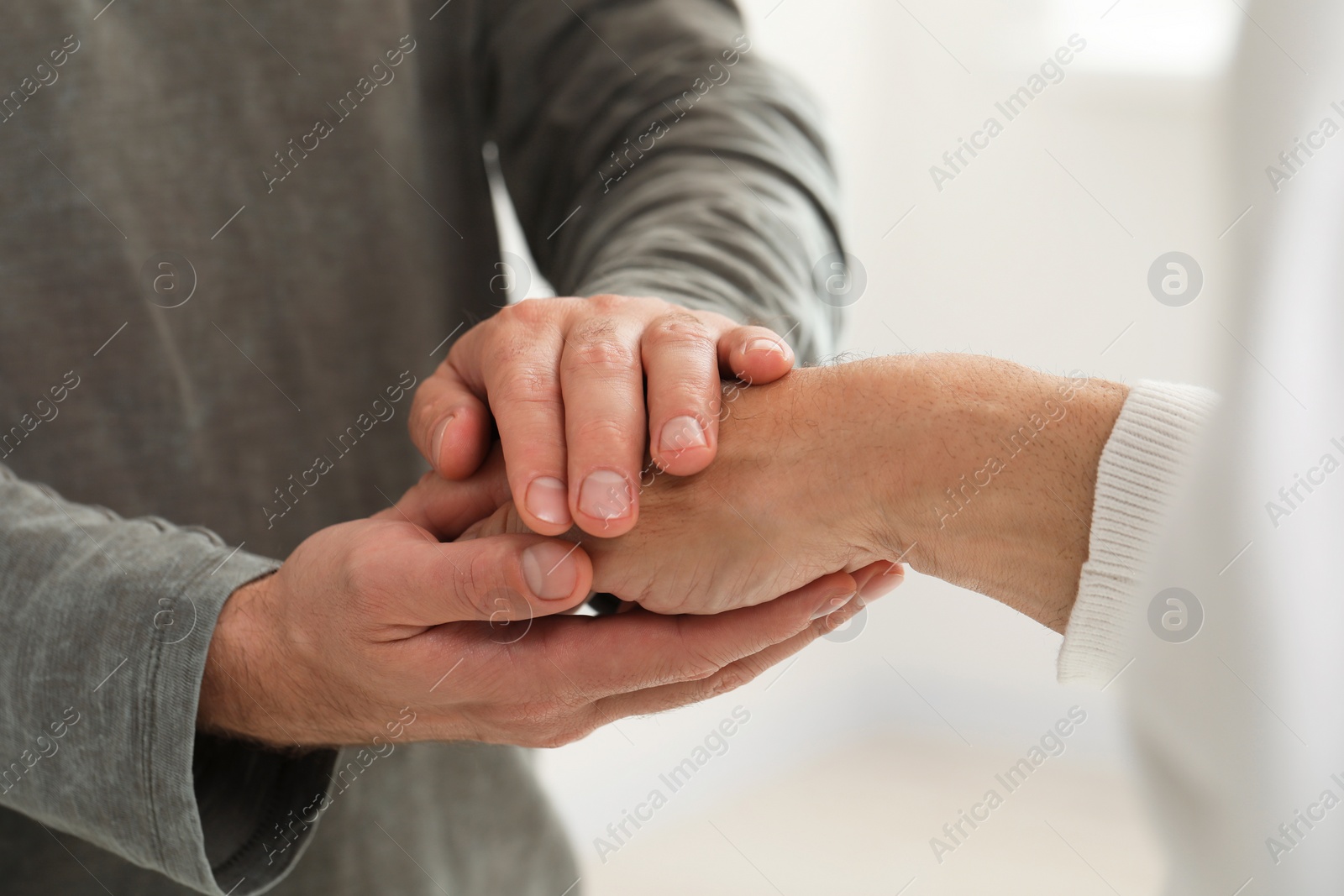 Photo of Trust and support. Men joining hands on blurred background, closeup