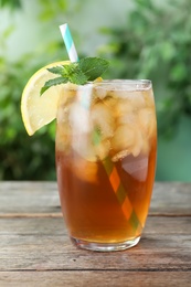 Photo of Delicious iced tea in glass on wooden table outdoors, closeup