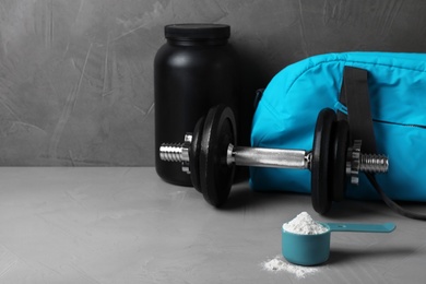 Composition with protein powder and dumbbell on table. Space for text