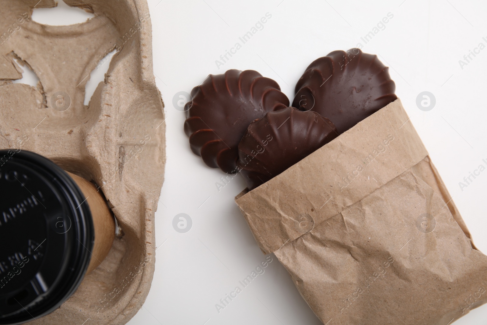 Photo of Delicious chocolate covered zephyrs and paper cup on white background, flat lay