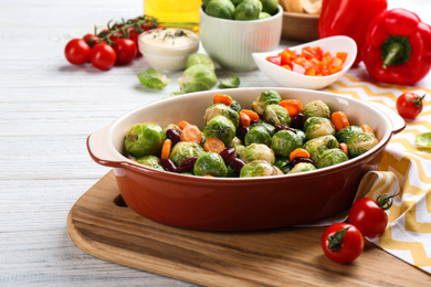 Photo of Roasted Brussels sprouts with beans and carrot in baking dish on white wooden table
