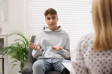 Psychologist working with teenage boy in office