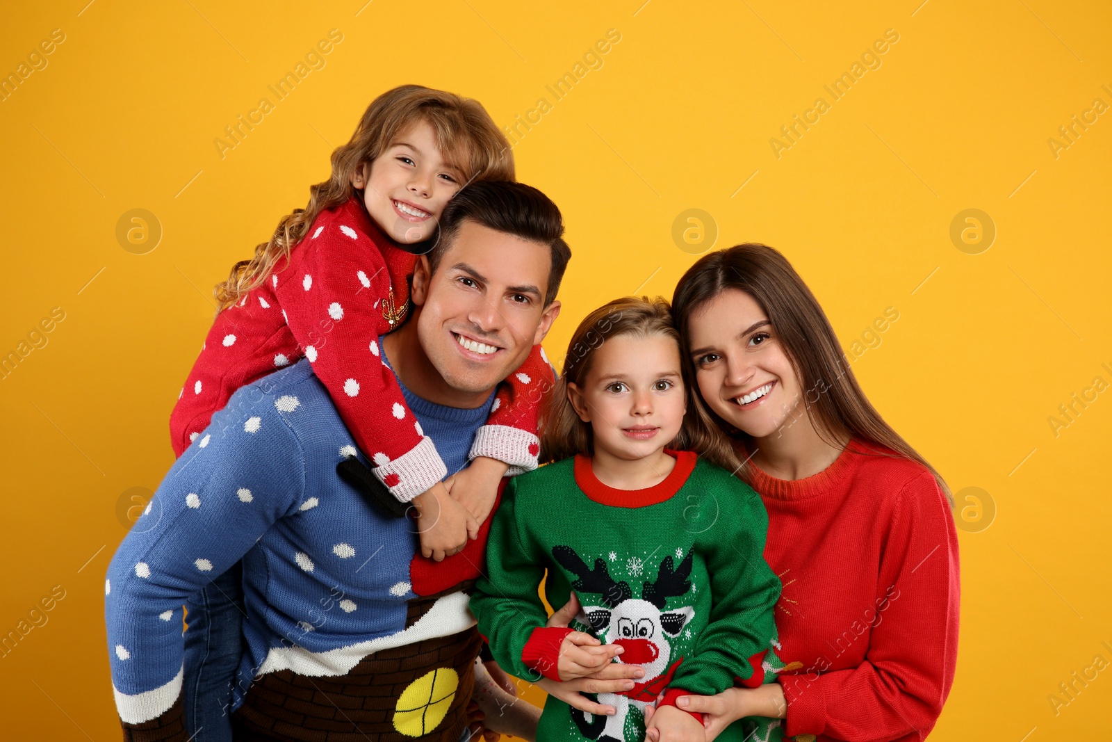 Photo of Family in Christmas sweaters on yellow background