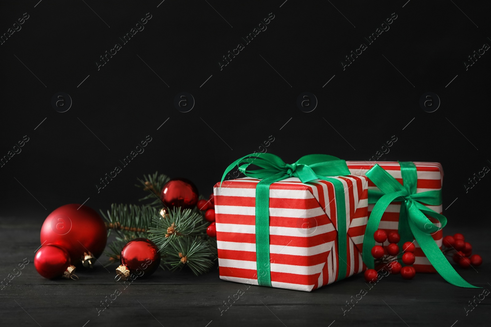 Photo of Gift boxes with Christmas balls and fir tree branches on black wooden table