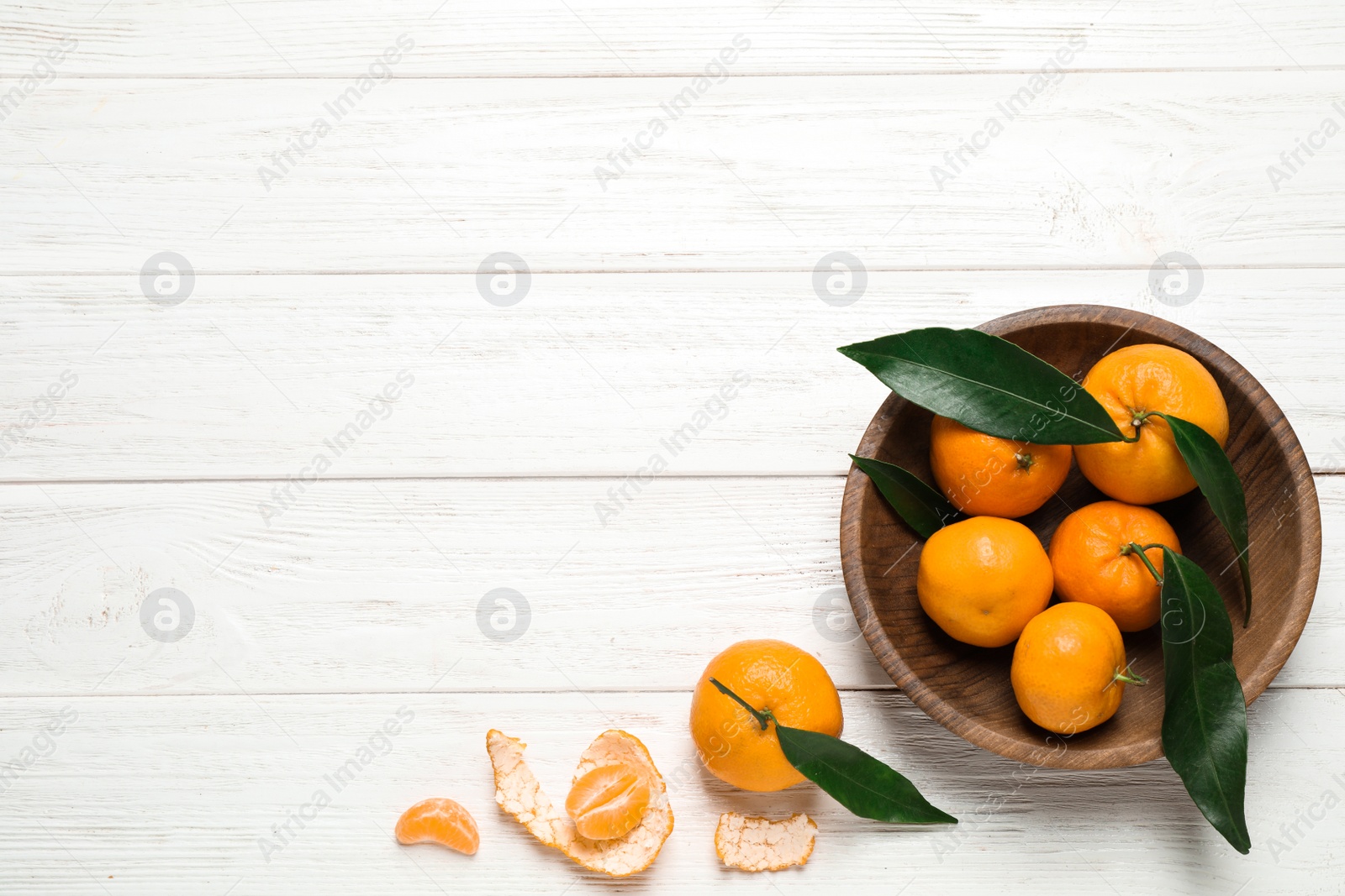 Photo of Fresh ripe tangerines with leaves and space for text on white wooden table, flat lay. Citrus fruit