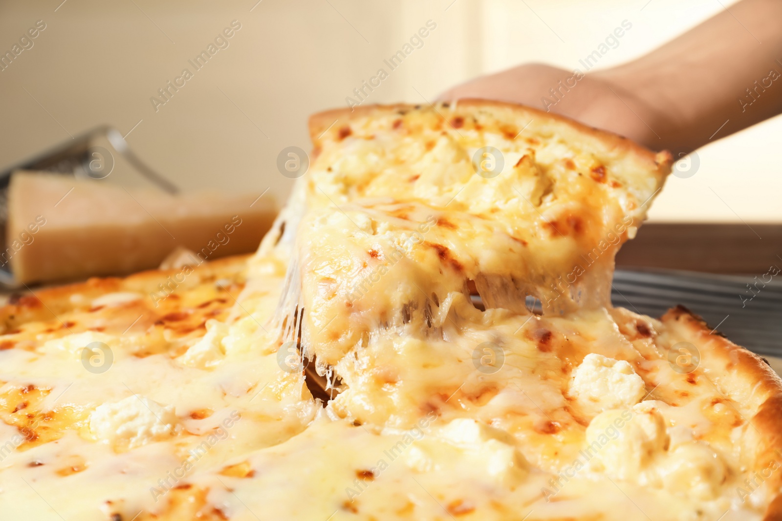 Photo of Woman holding slice of delicious hot pizza over table, closeup