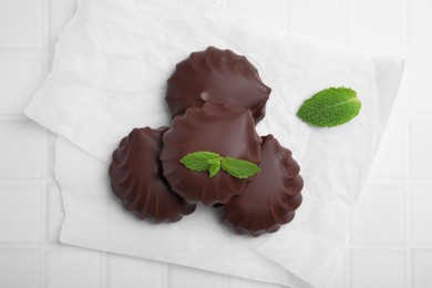 Photo of Delicious chocolate covered zephyrs with mint on white table, flat lay
