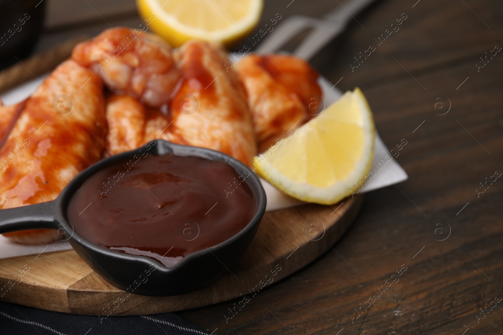 Photo of Fresh marinade, raw chicken wings and lemon on table, closeup