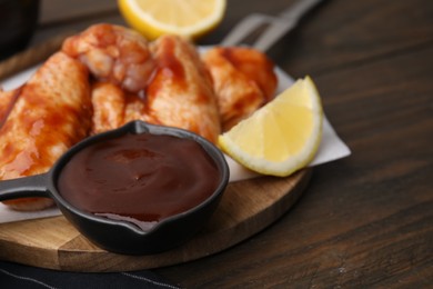 Photo of Fresh marinade, raw chicken wings and lemon on table, closeup