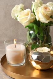 Photo of Tray with burning wax candles and flowers on table