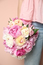 Photo of Woman with bouquet of beautiful peonies on beige background, closeup