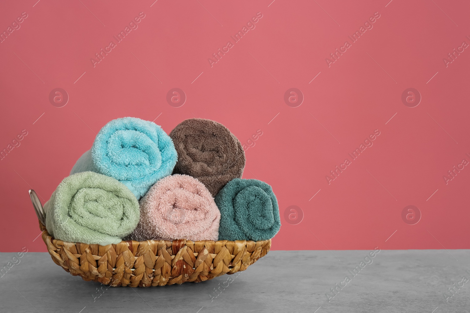 Photo of Rolled color towels on light grey stone table. Space for text