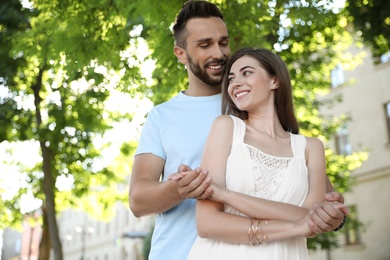 Lovely young couple dancing together in park on sunny day