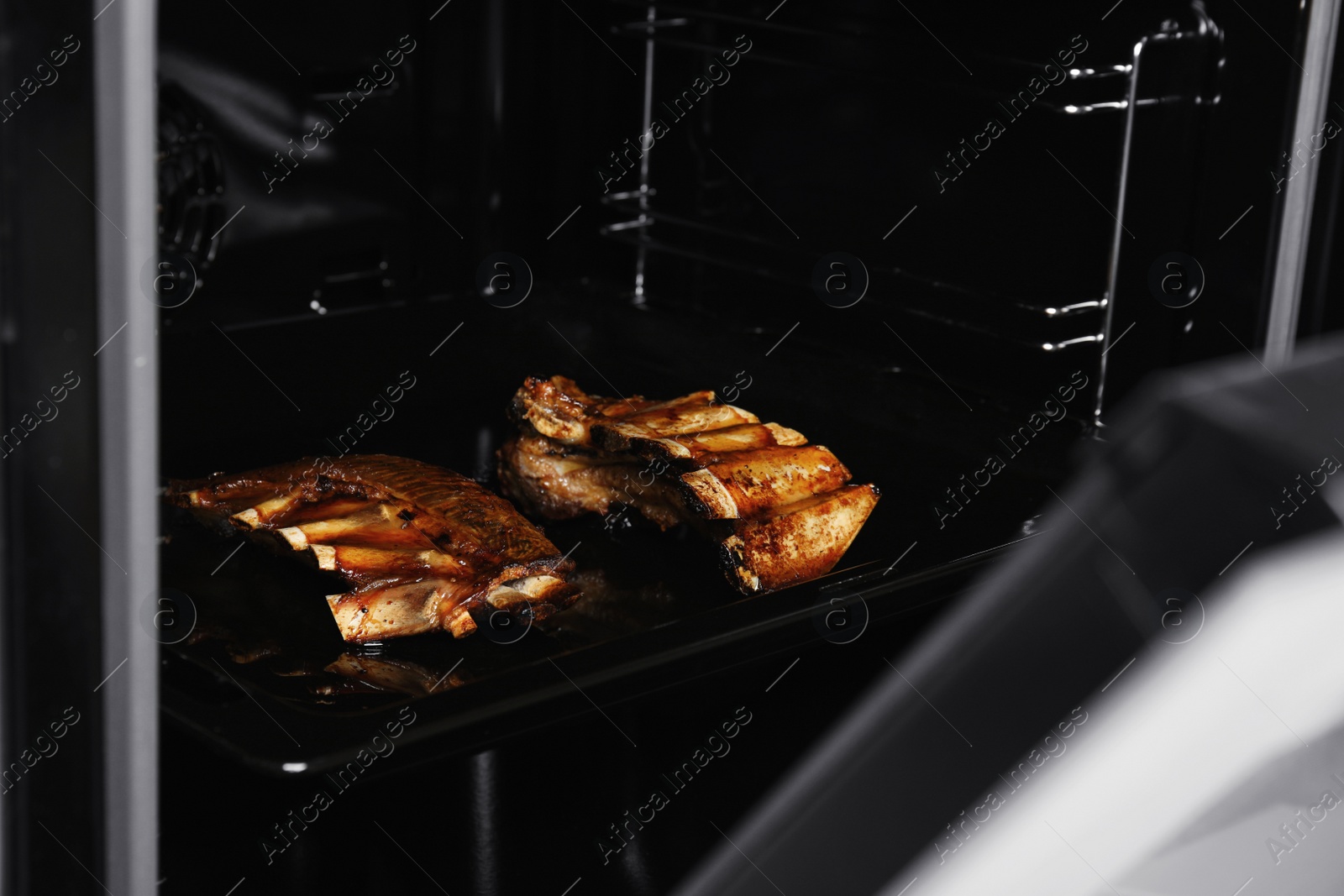 Photo of Delicious roasted ribs on baking sheet in oven