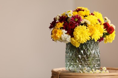 Photo of Bouquet of beautiful chrysanthemum flowers on wicker table indoors, space for text
