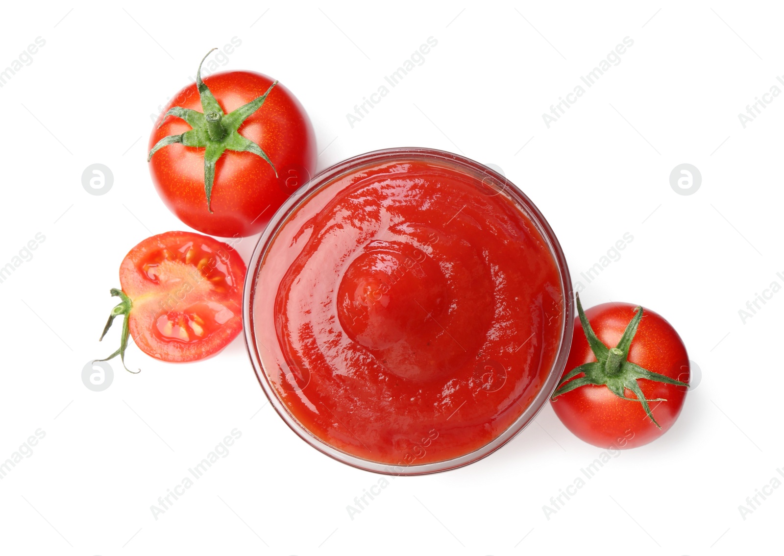 Photo of Tasty ketchup in glass bowl and fresh tomatoes isolated on white, top view