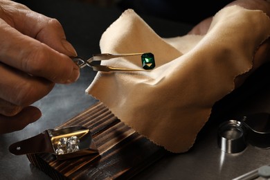 Photo of Professional jeweler working with gemstone at table, closeup