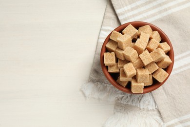 Photo of Brown sugar cubes on white wooden table, top view. Space for text