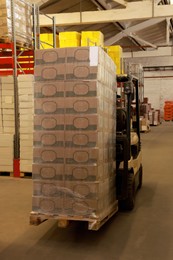 Image of Forklift truck with boxes in warehouse. Logistics concept