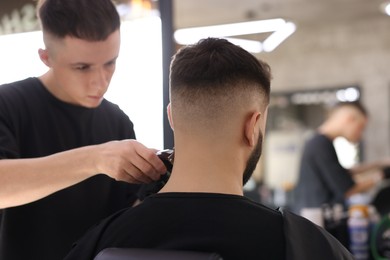 Professional hairdresser working with client in barbershop