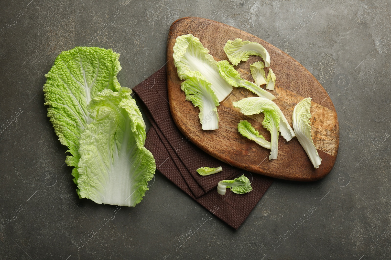 Photo of Pieces of fresh Chinese cabbage on gray textured table, top view