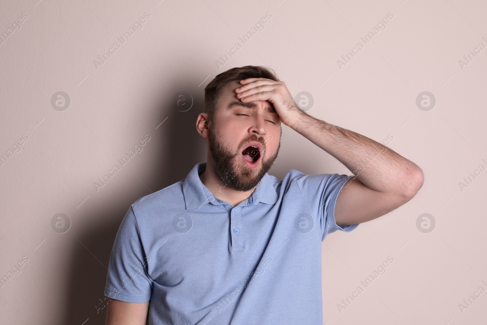 Photo of Sleepy young man yawning on beige background