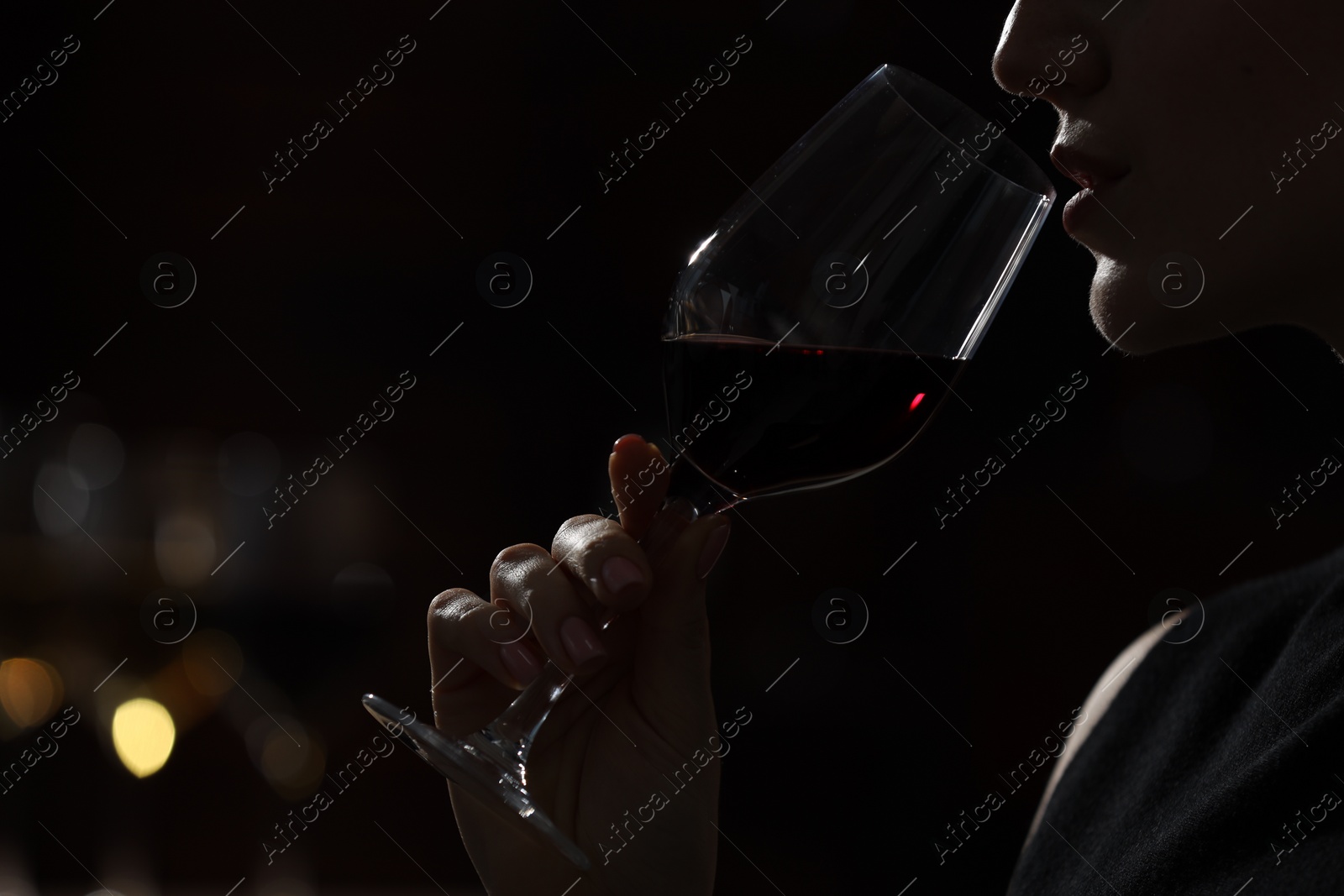 Photo of Woman with glass of red wine against blurred background, closeup. Space for text