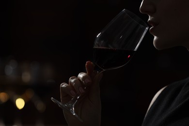 Woman with glass of red wine against blurred background, closeup. Space for text