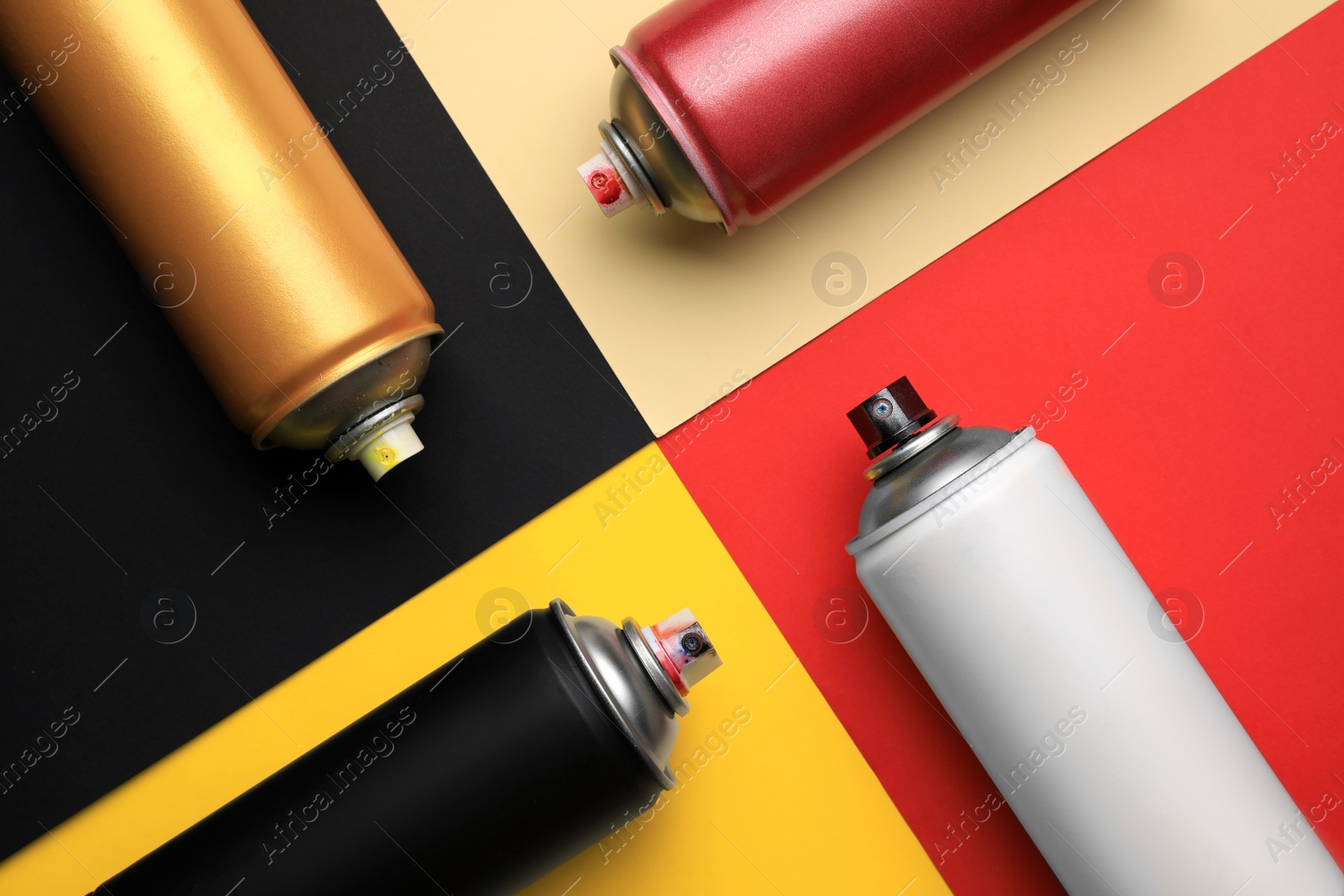 Photo of Cans of different graffiti spray paints on color background, flat lay