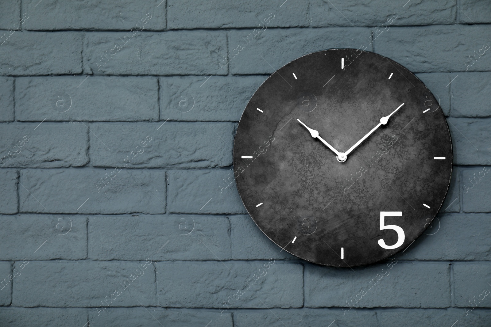 Photo of Modern clock on brick wall. Time concept