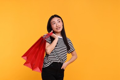 Photo of Smiling woman with shopping bags on yellow background. Space for text