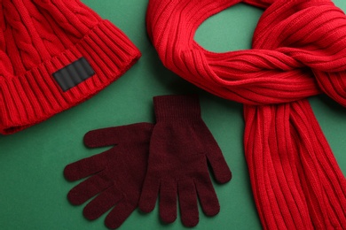 Stylish gloves, scarf and hat on green background, above view