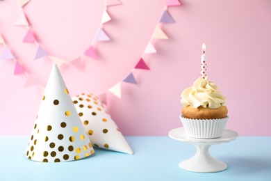 Dessert stand with delicious birthday cupcake on color background