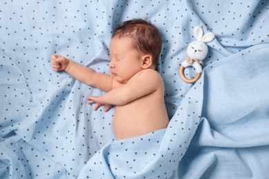 Cute newborn baby with toy bunny sleeping on bed, top view