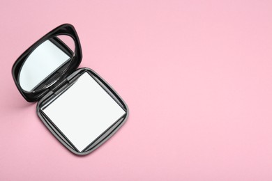 Photo of Stylish cosmetic pocket mirror on pink background, top view. Space for text