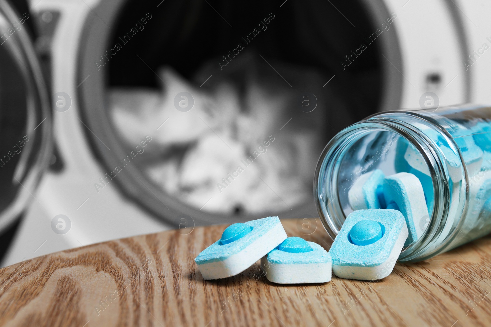 Photo of Jar with water softener tablets on wooden table near washing machine, space for text