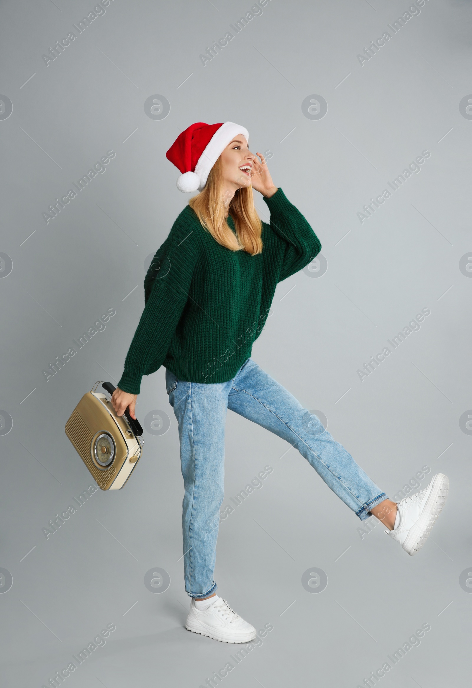 Photo of Happy woman with vintage radio on grey background. Christmas music