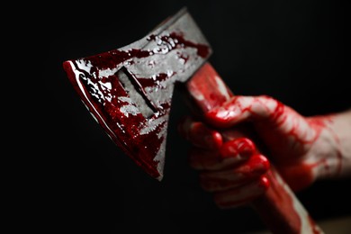 Photo of Man holding bloody axe on black background, closeup