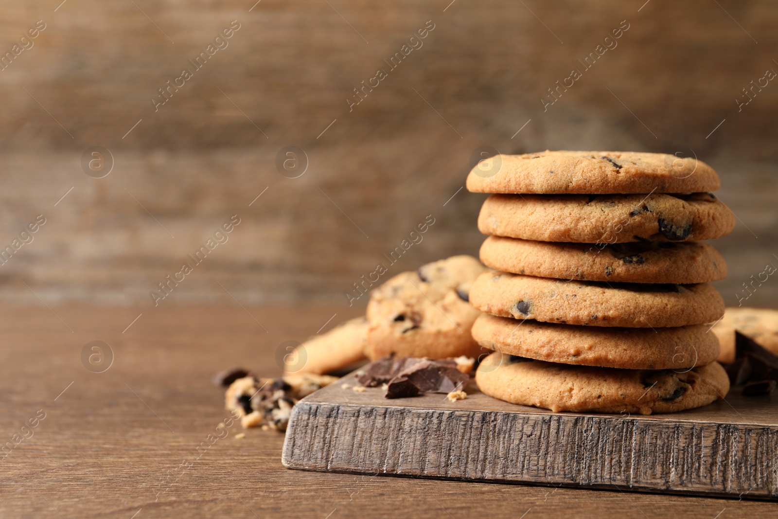 Photo of Delicious chocolate chip cookies on wooden table. Space for text