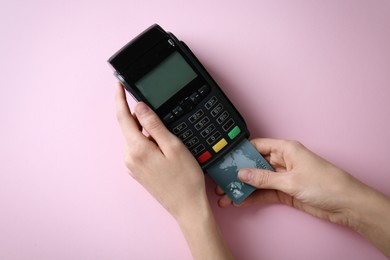 Photo of Woman with credit card using modern payment terminal on pink background, top view