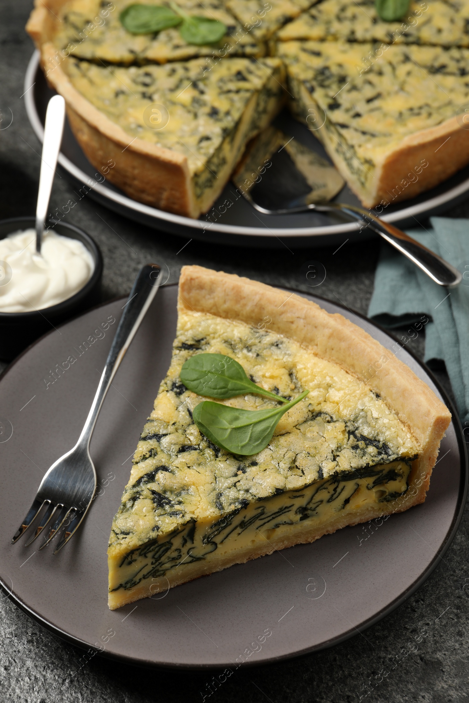 Photo of Piece of delicious spinach pie served on grey table