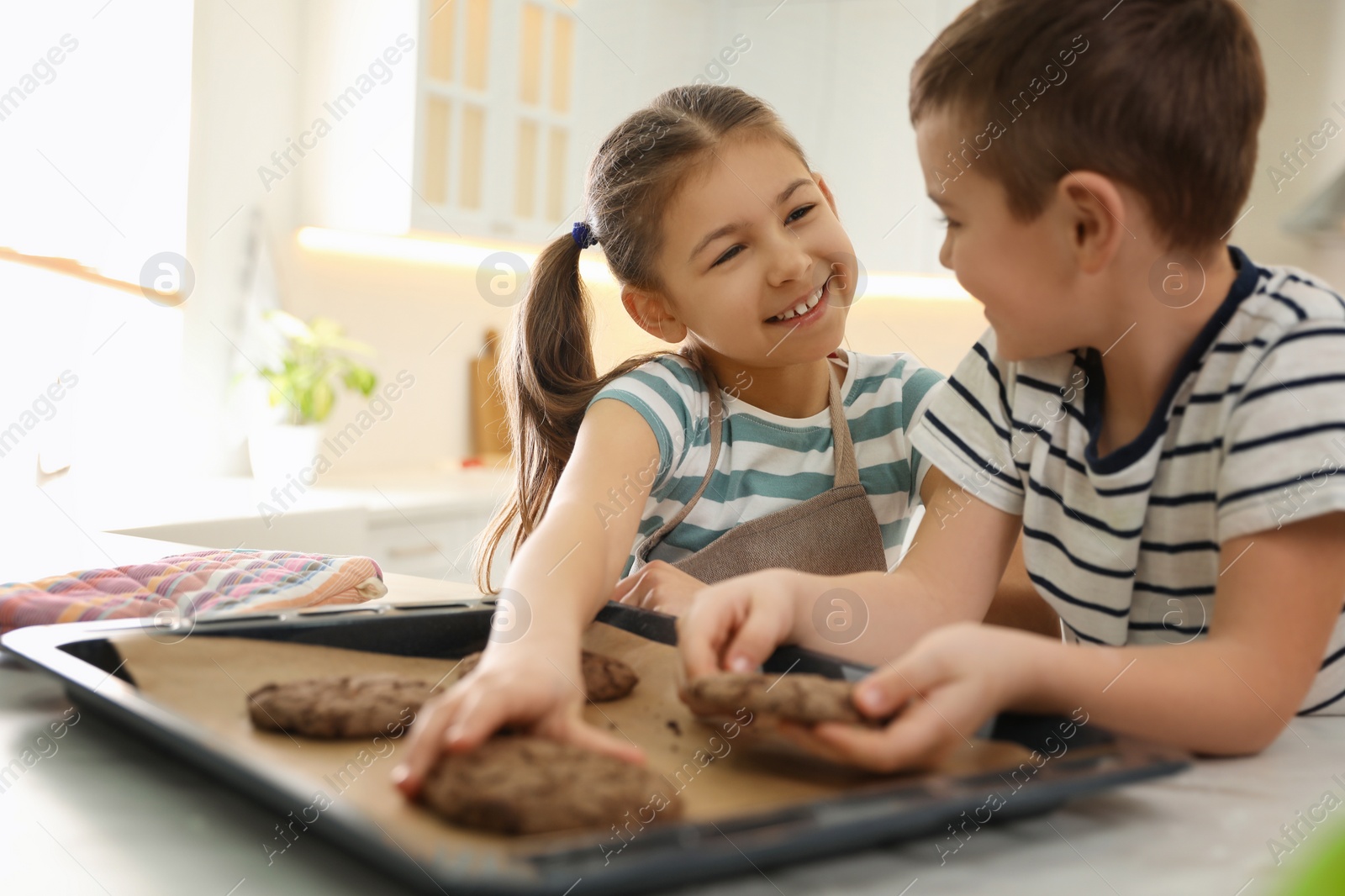 Photo of Cute little children with fresh delicious cookies in kitchen. Cooking together