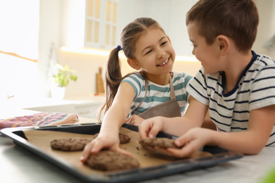 Cute little children with fresh delicious cookies in kitchen. Cooking together