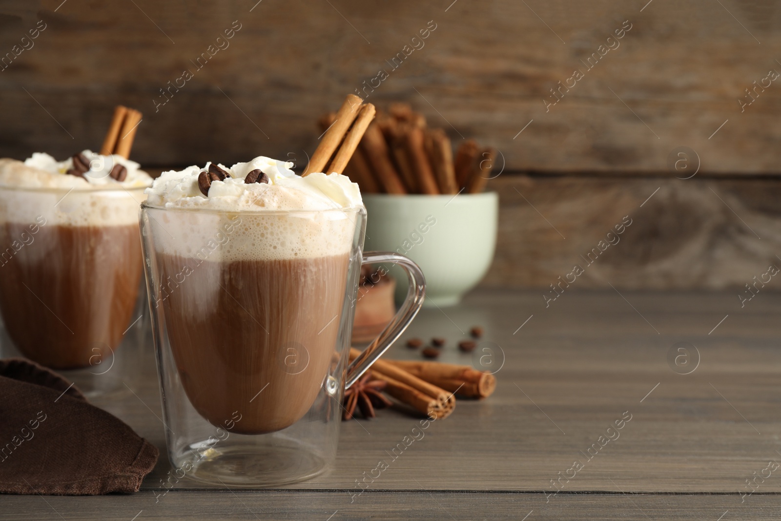 Photo of Delicious coffee with whipped cream and cinnamon on wooden table. Space for text