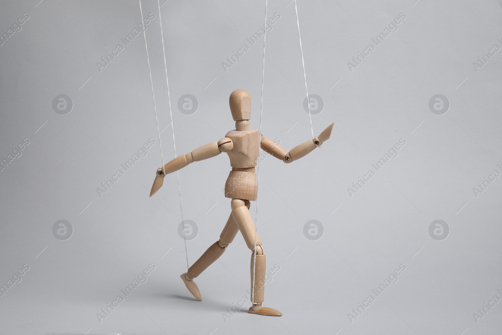 Photo of One wooden puppet with strings on light grey background