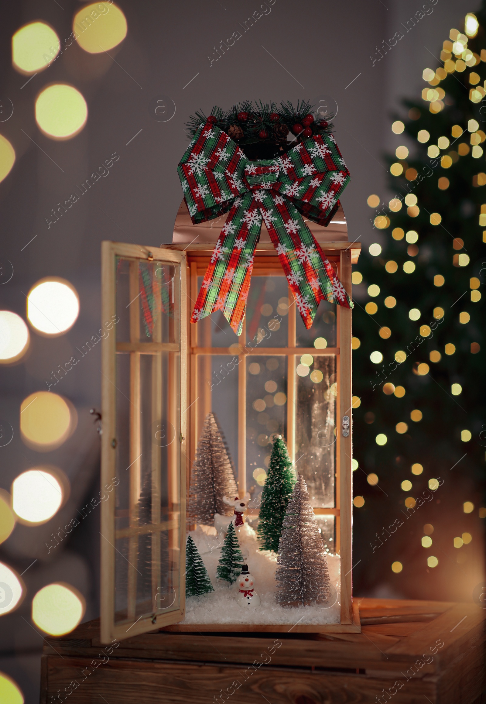 Photo of Vintage wooden lantern with beautiful Christmas composition surrounded by blurred festive lights indoors