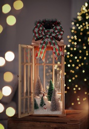 Vintage wooden lantern with beautiful Christmas composition surrounded by blurred festive lights indoors